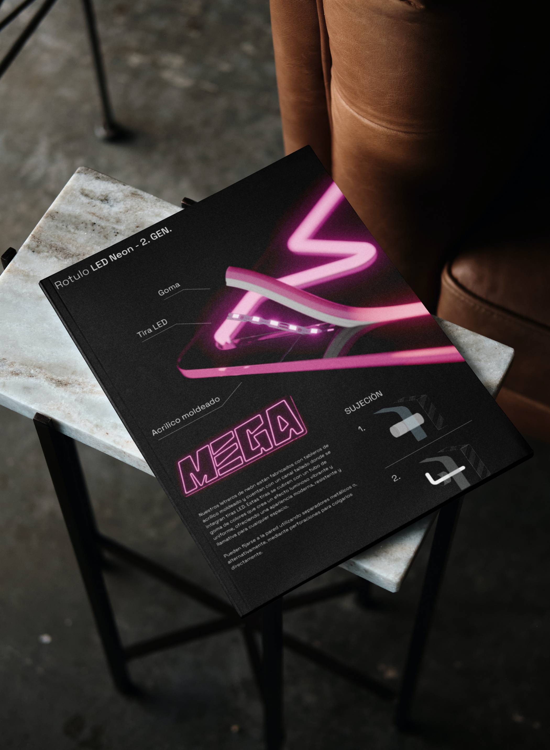 Black MEGA booklet with pink neon artwork on a chair